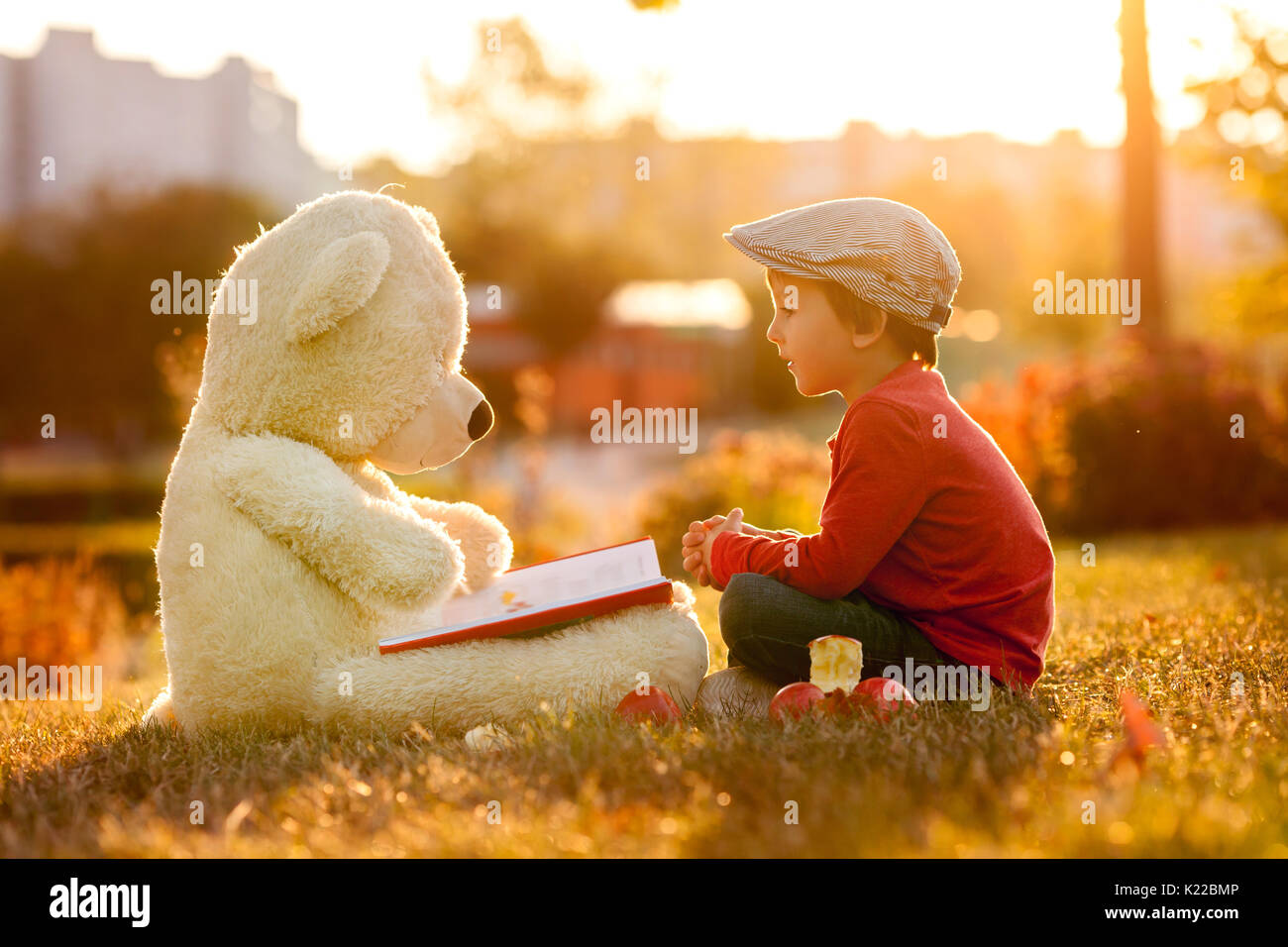 Adorable little boy with his teddy bear friend in the park on sunset ...