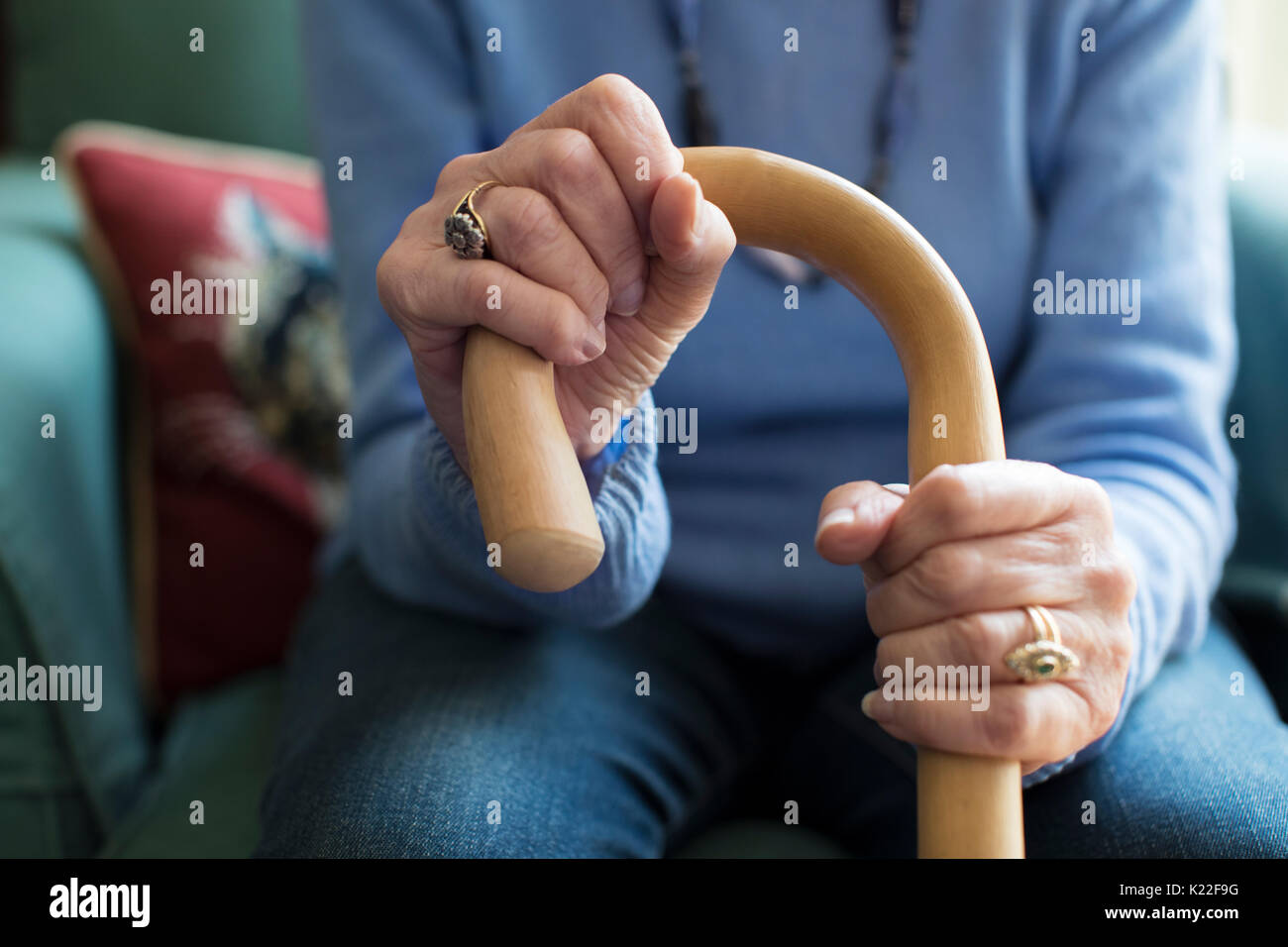Close Up Of Senior Woman Sitting In Chair Holding Walking Cane Stock Photo
