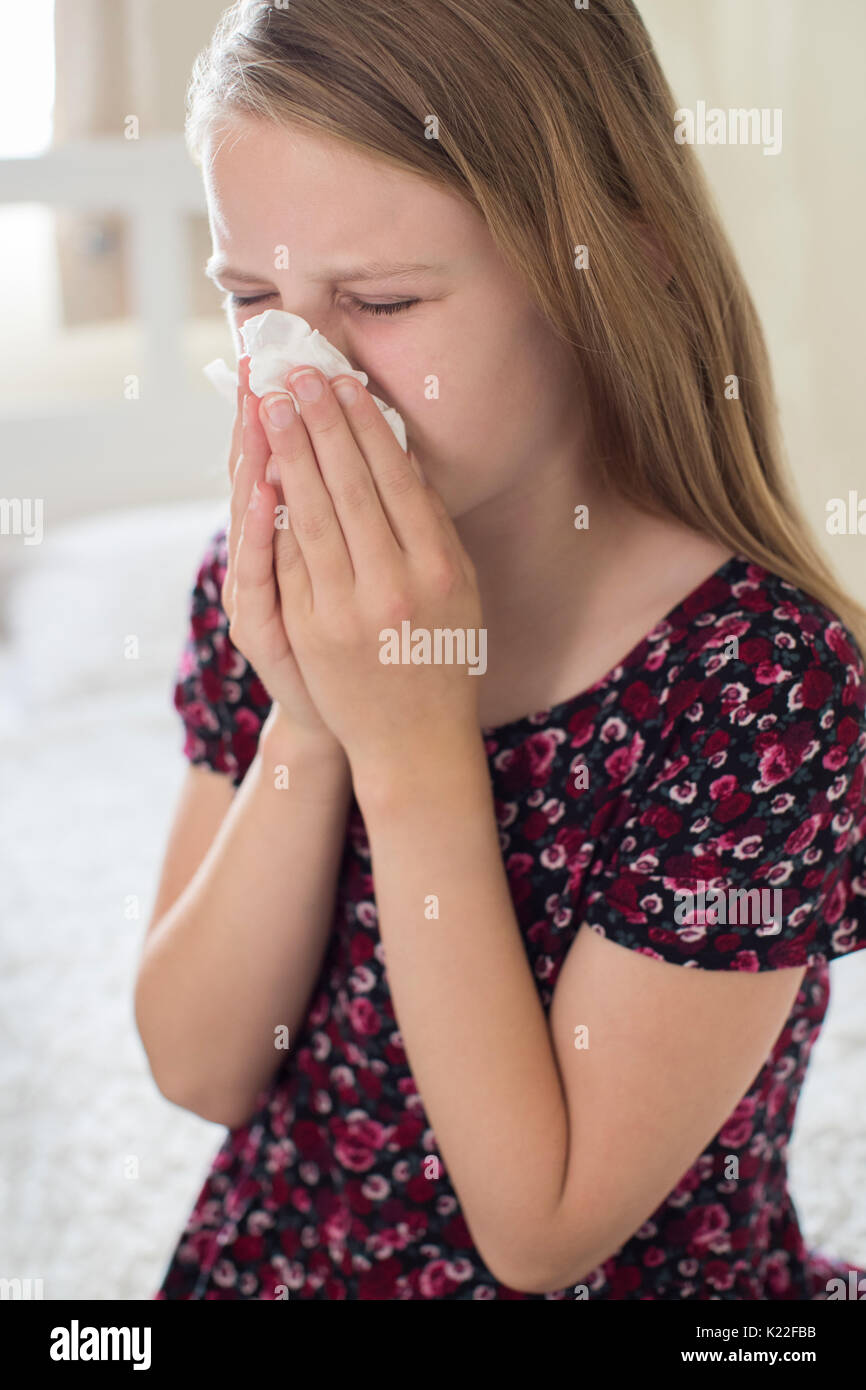 Girl Suffering With Cold Sneezing Into Tissue Stock Photo