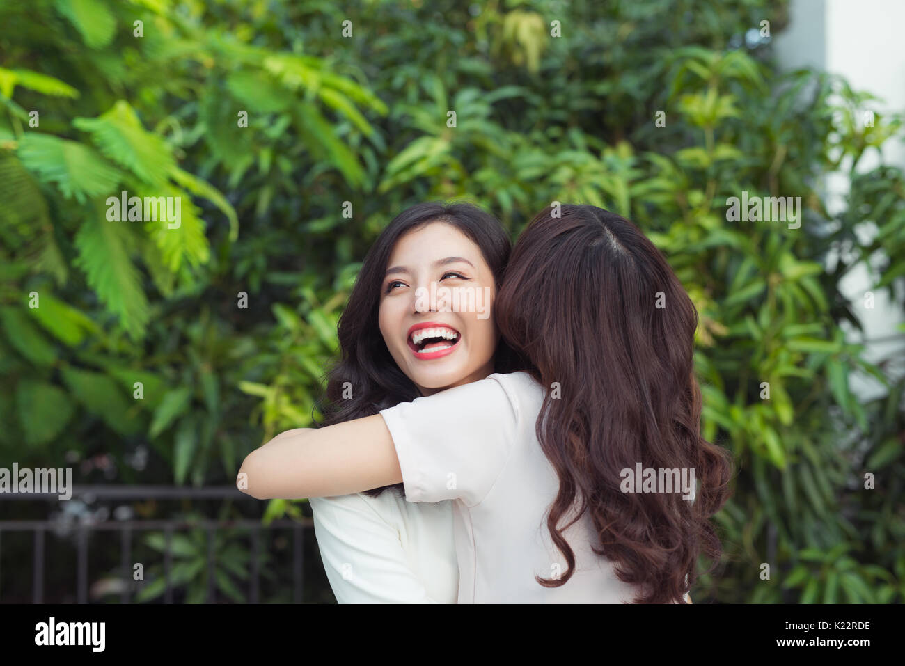 Happy young women friends well-dressed smiling while hugging together Stock Photo