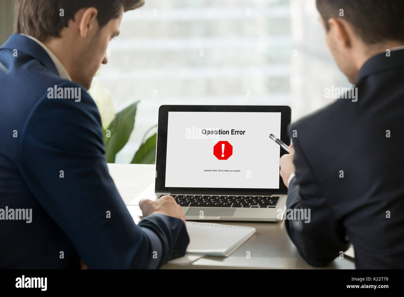 Two businessmen looking at broken laptop, operating system crash Stock Photo