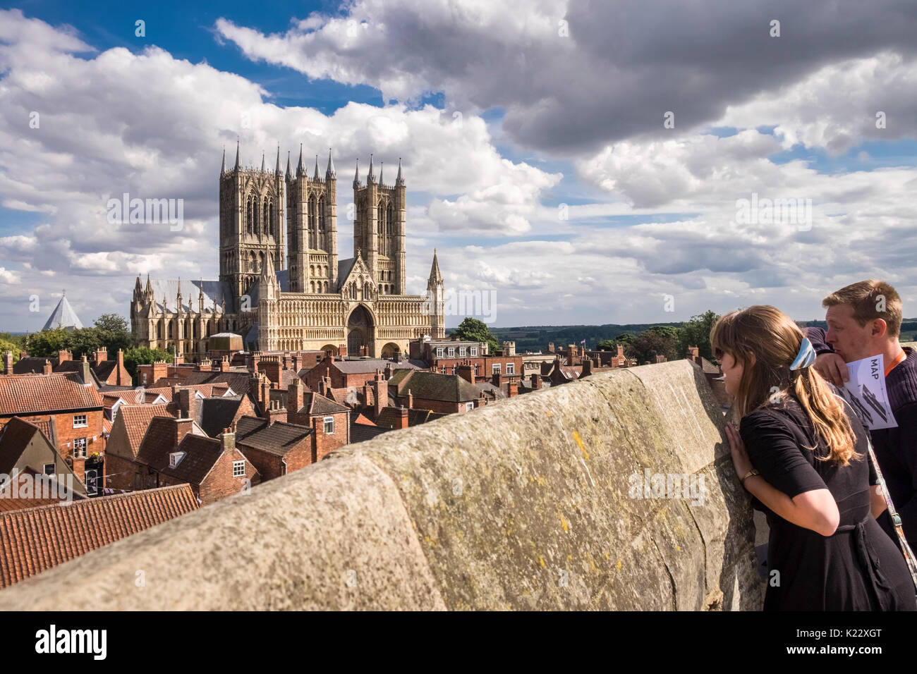 Young man and woman viewing gothic architecture of Lincoln Cathedral on summer day from Lincoln Castle walls, City of Lincoln, Lincolnshire, UK Stock Photo
