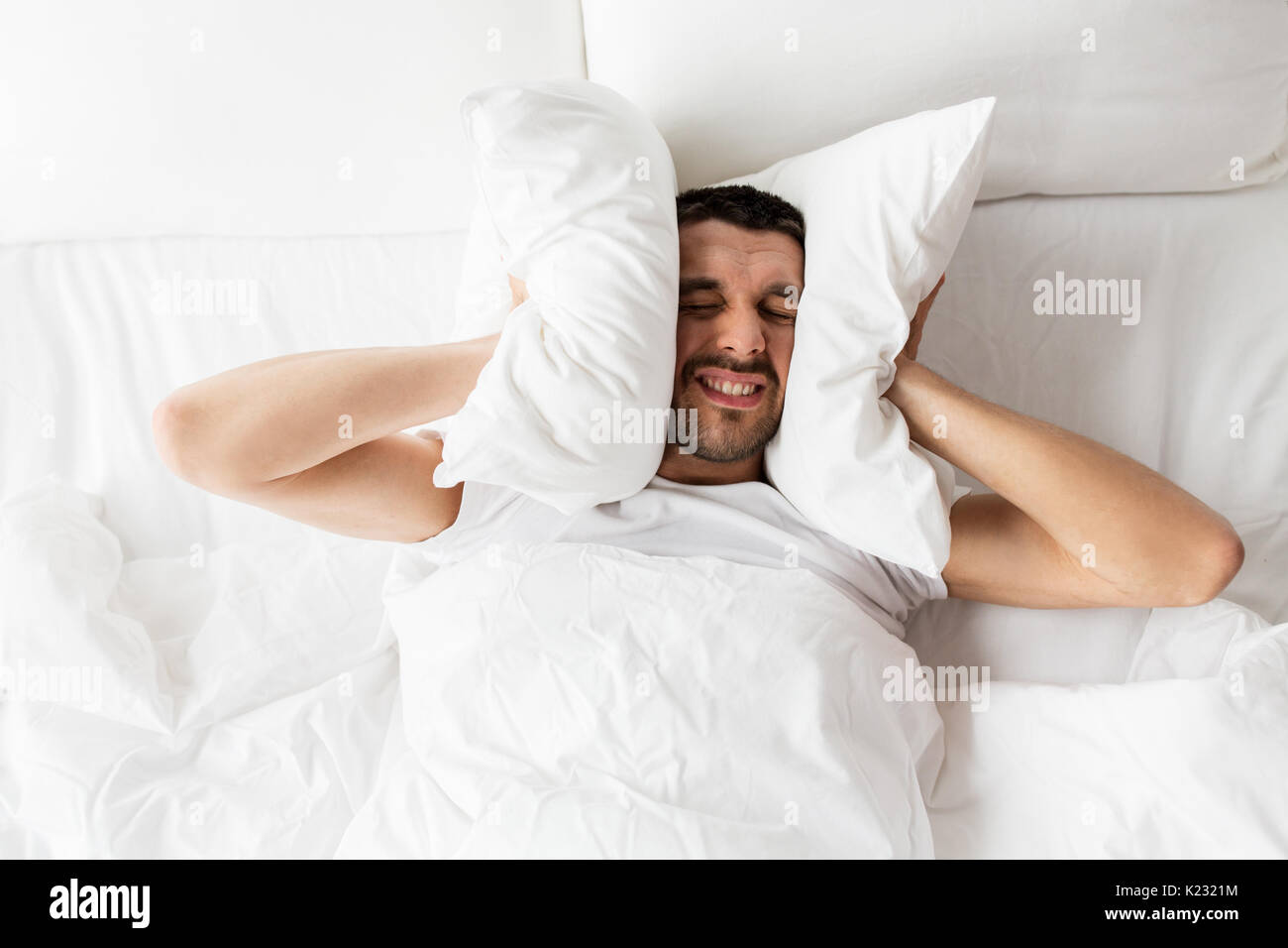 man in bed with pillow suffering from noise Stock Photo Alamy