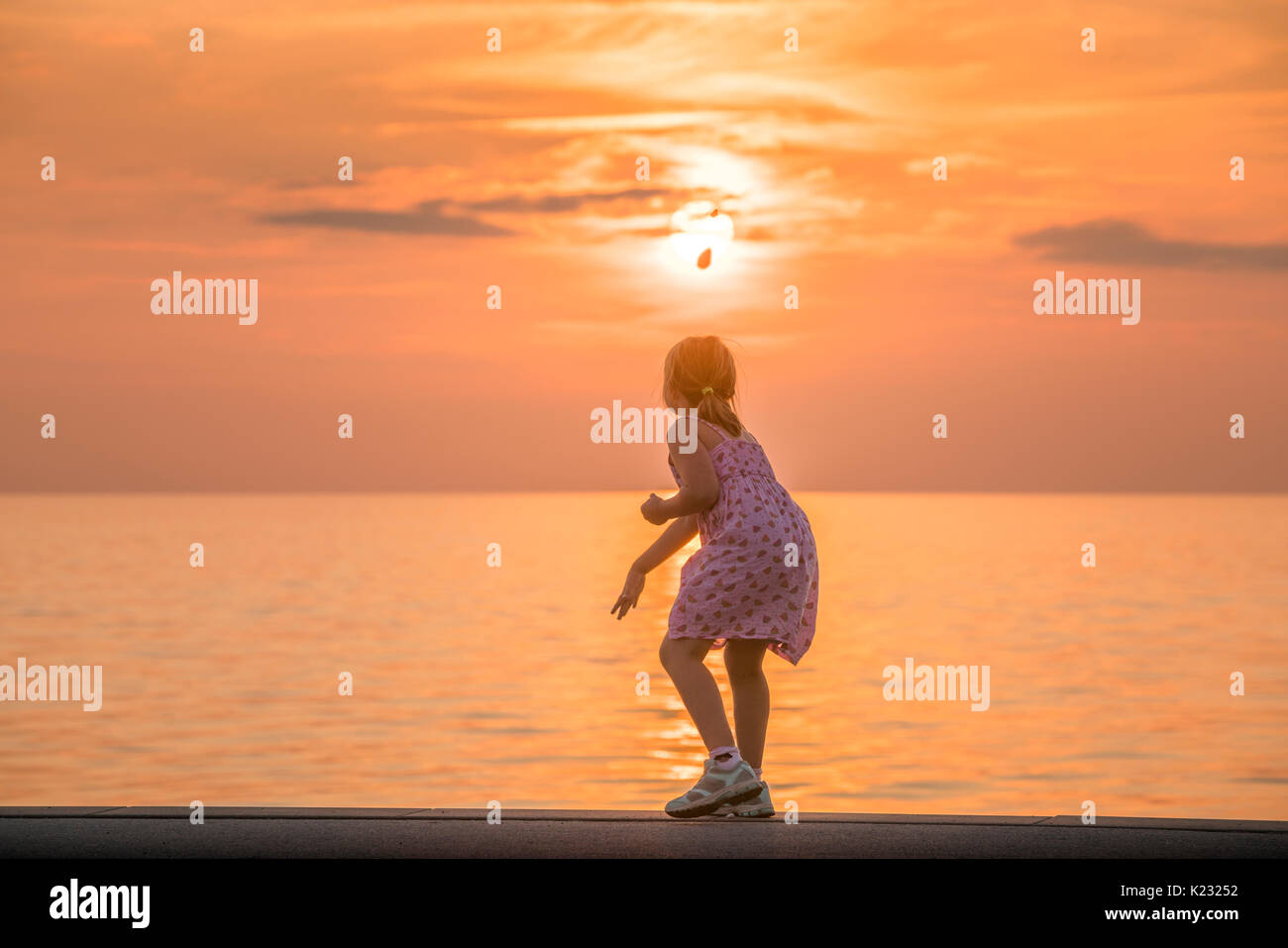 Young Girl By The Sea At Sunset Throwing Rocks In The Water Visby Stock Photo Alamy