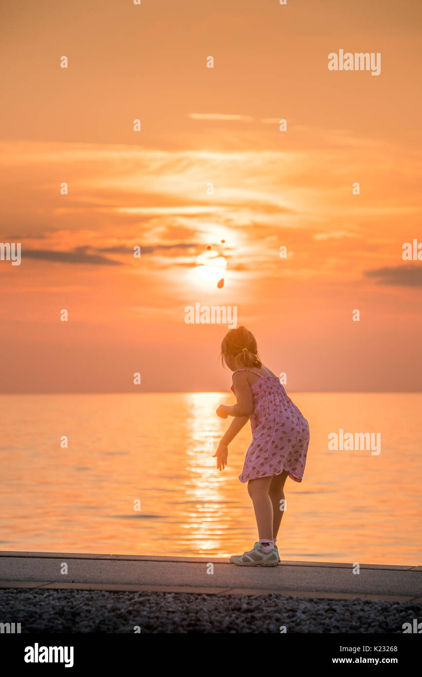 Young Girl By The Sea At Sunset Throwing Rocks In The Water Visby Stock Photo Alamy