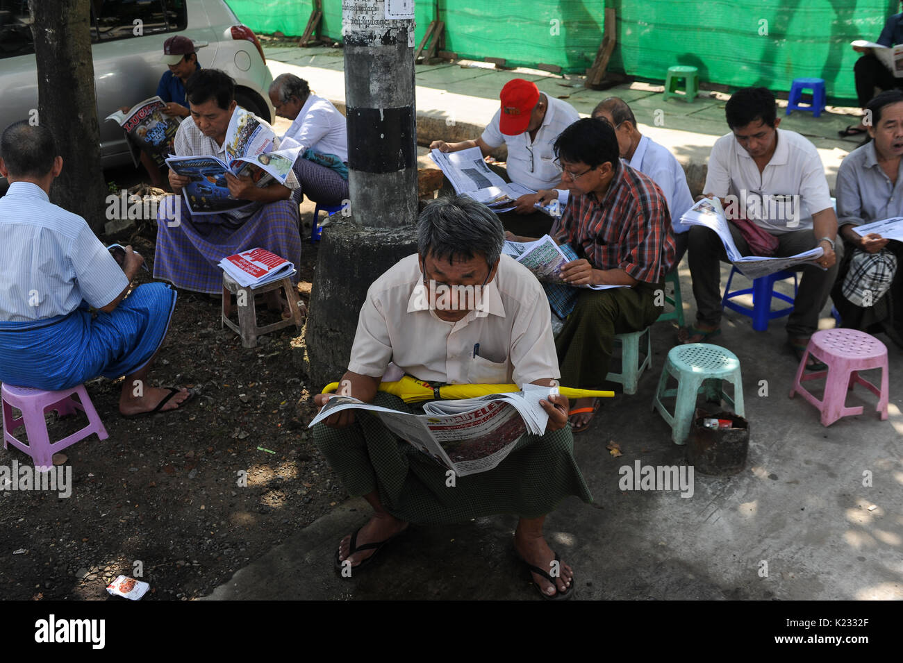 30.10.2015, Yangon, Republic of the Union of Myanmar, Asia - Local men read the newspaper at a roadside in the center of the former Burmese capital. Stock Photo