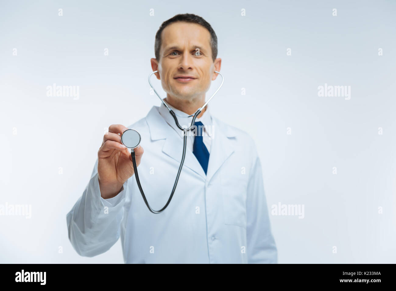 Friendly looking doctor listening to heart with stethoscope Stock Photo