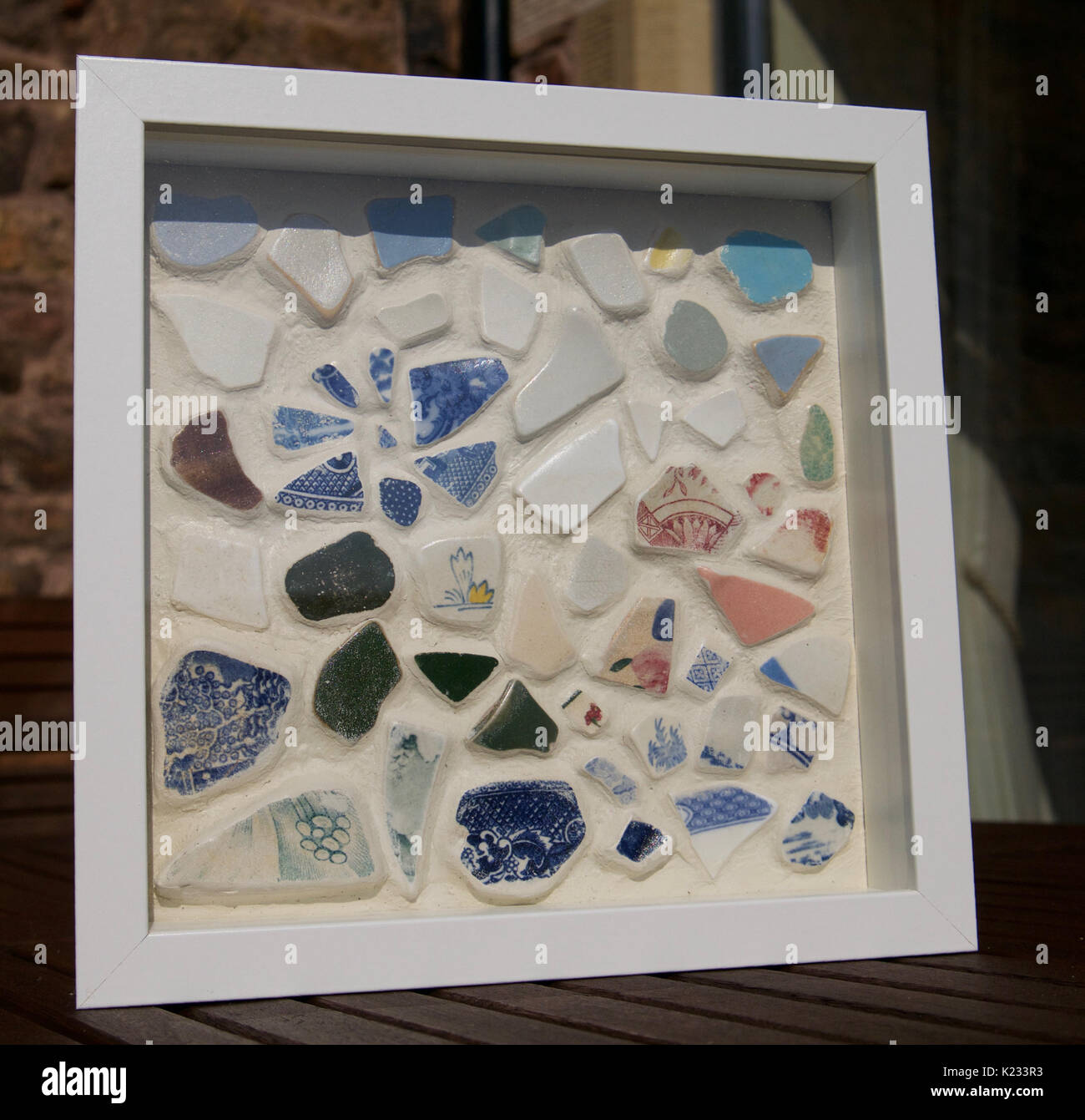 Close up of handmade sea worn pottery mosaic art work set in grout in