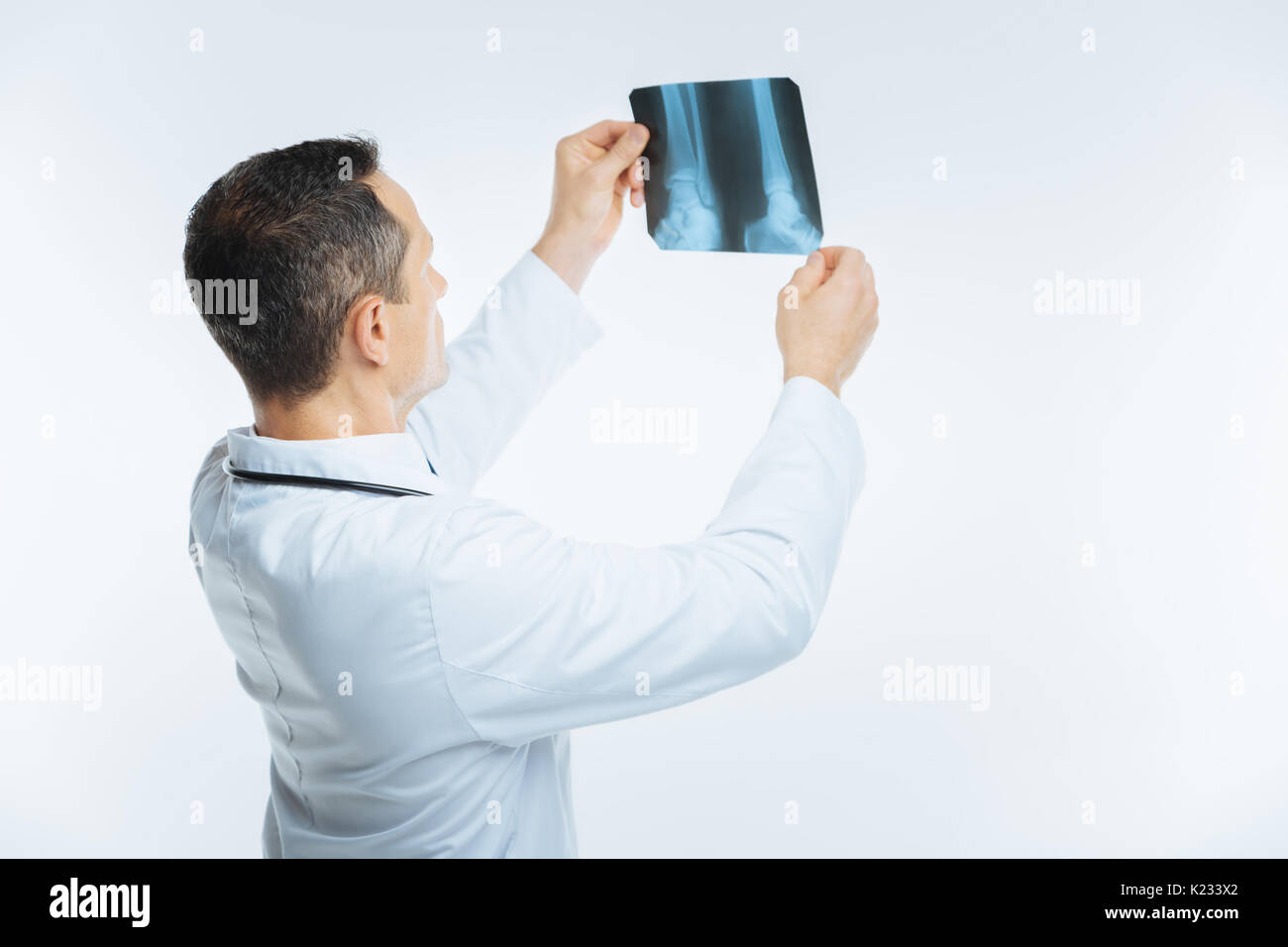 Turned back medical professional examining magnetic resonance image of leg Stock Photo
