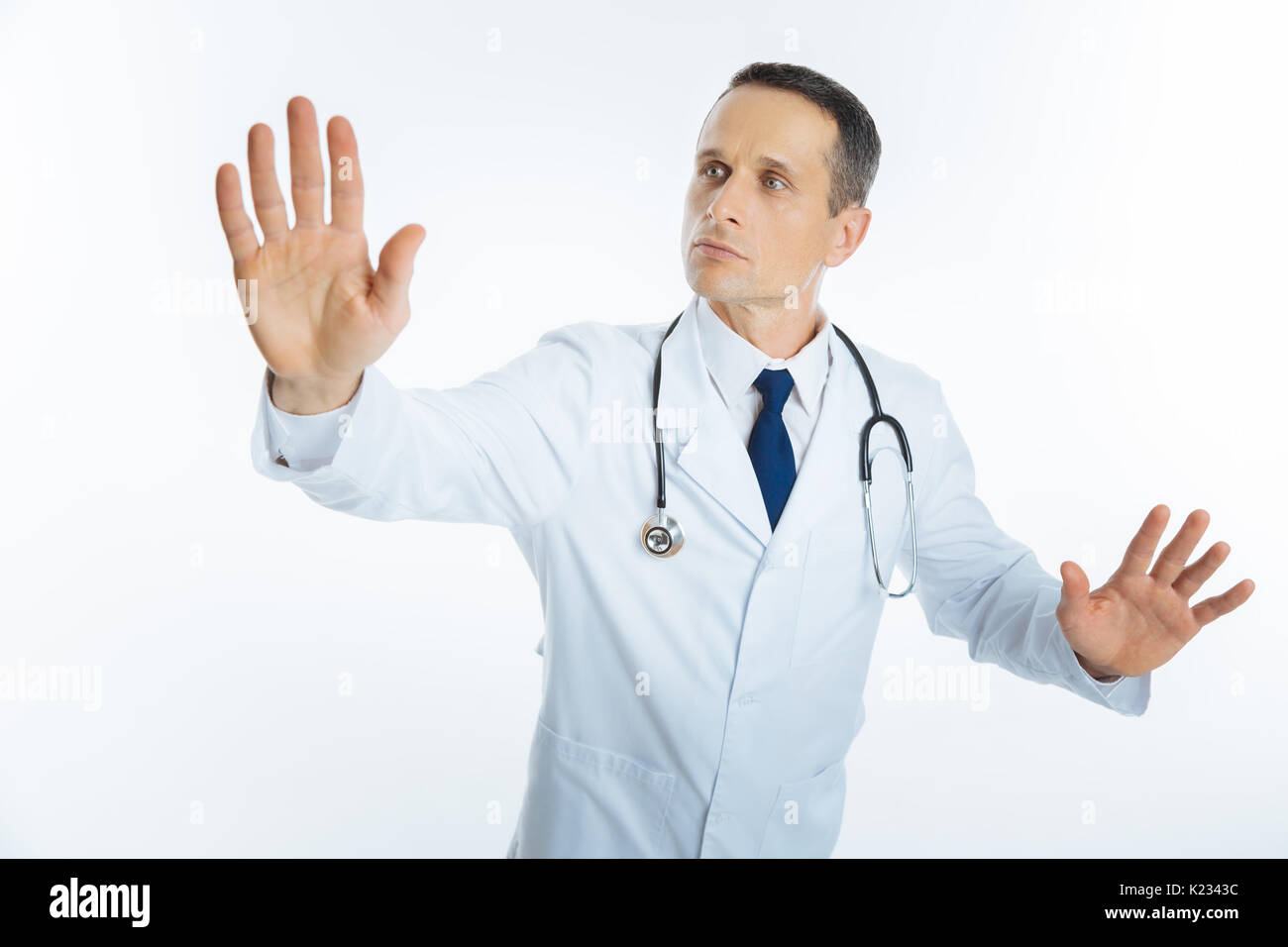 Male physician with stethoscope touching invisible screen Stock Photo