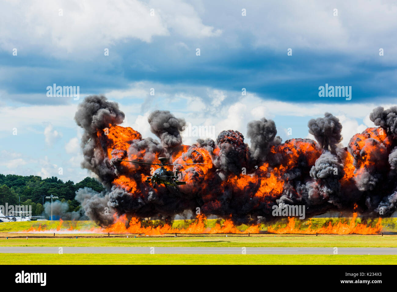 The Apache Helicopter giving a flying display at the 2016 Farnborough Airshow with pyrotechnics adding to the excitement and to show off its agility Stock Photo