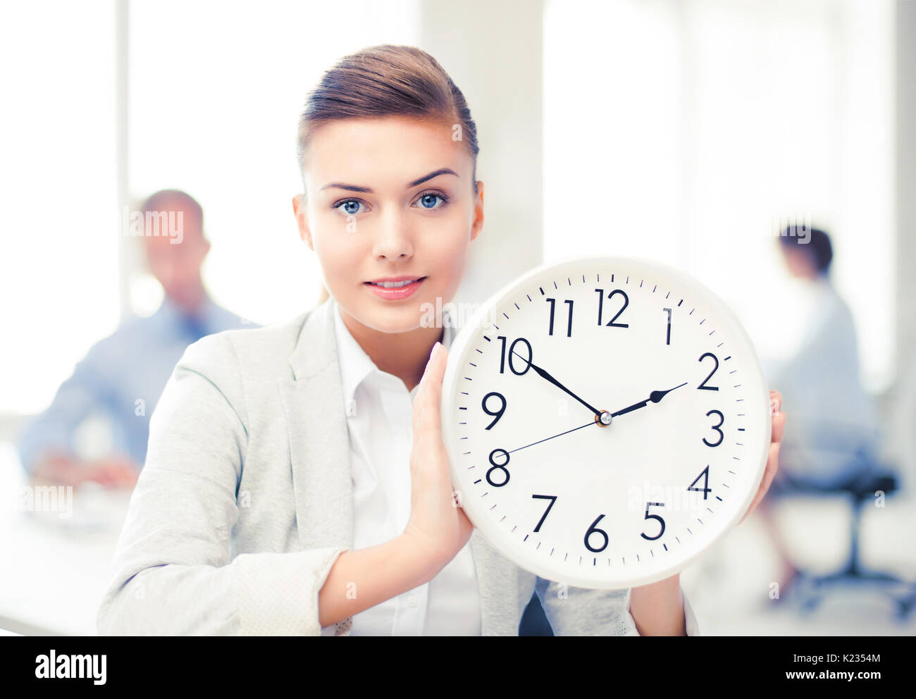 businesswoman showing white clock in office Stock Photo Alamy