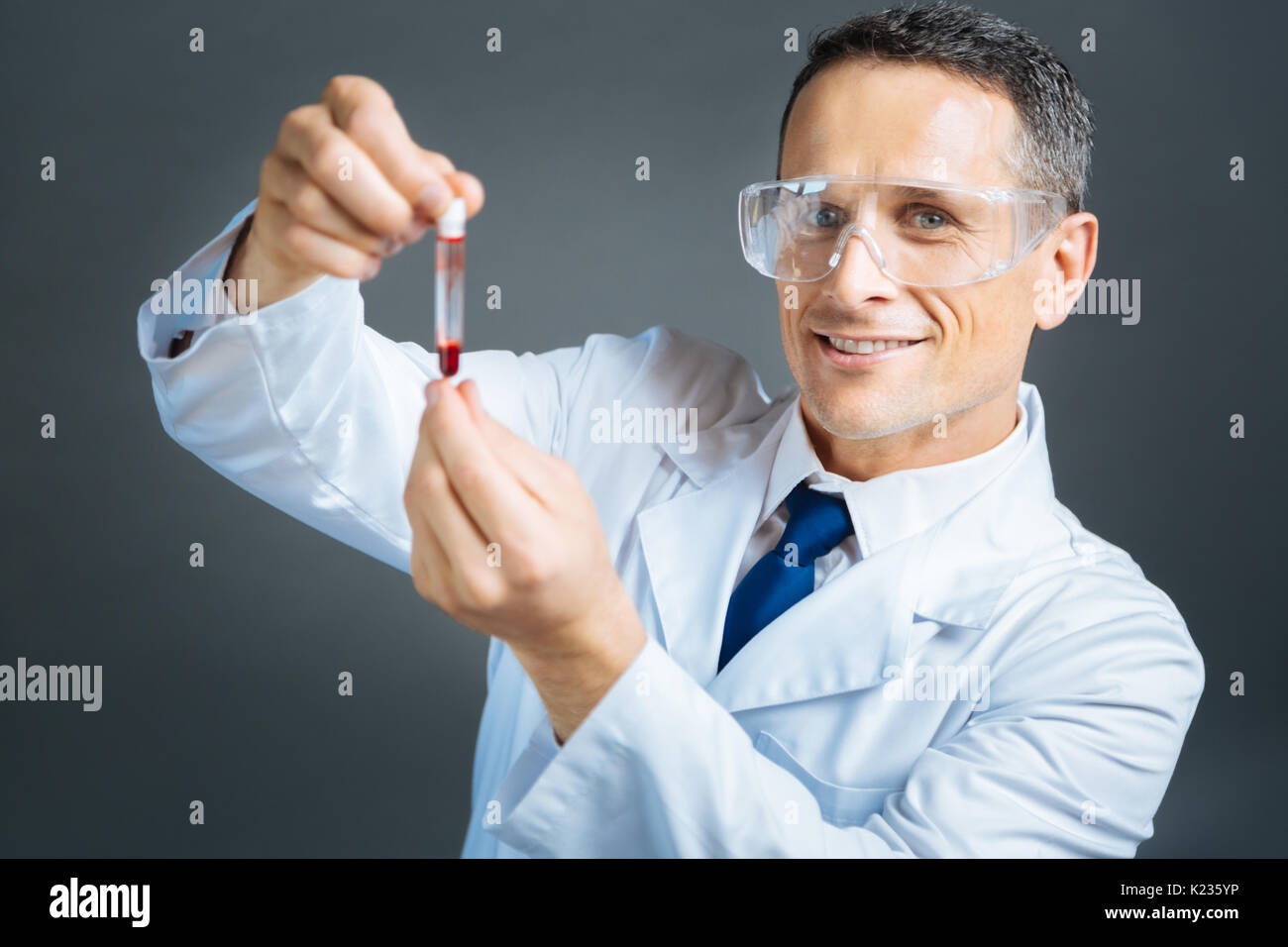 Radiant practitioner with blood sample smiling into camera Stock Photo