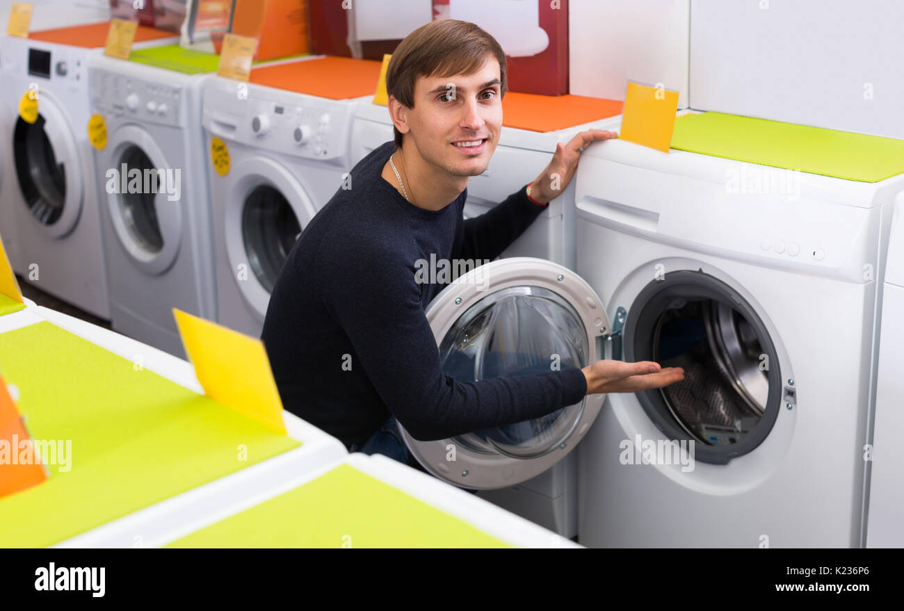Smiling male customer looking at washers and dryers in store Stock