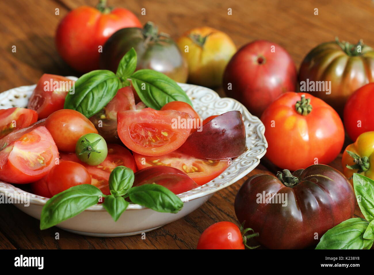 Colorful tomatoes salad with basil and balsamic vinegar on wooden rustic background Stock Photo