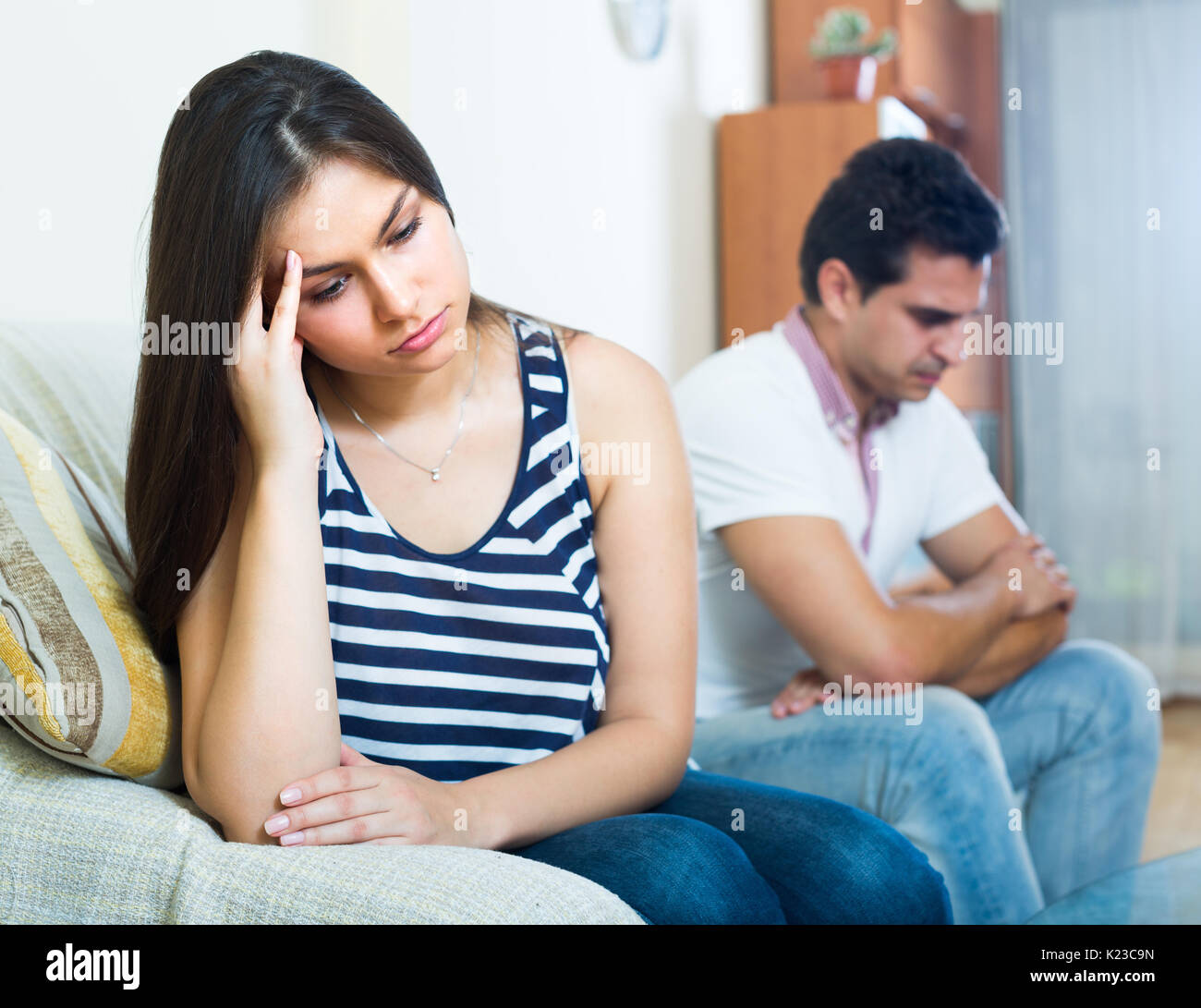 Young sulking man and woman blaming each other during indoor quarrel Stock Photo