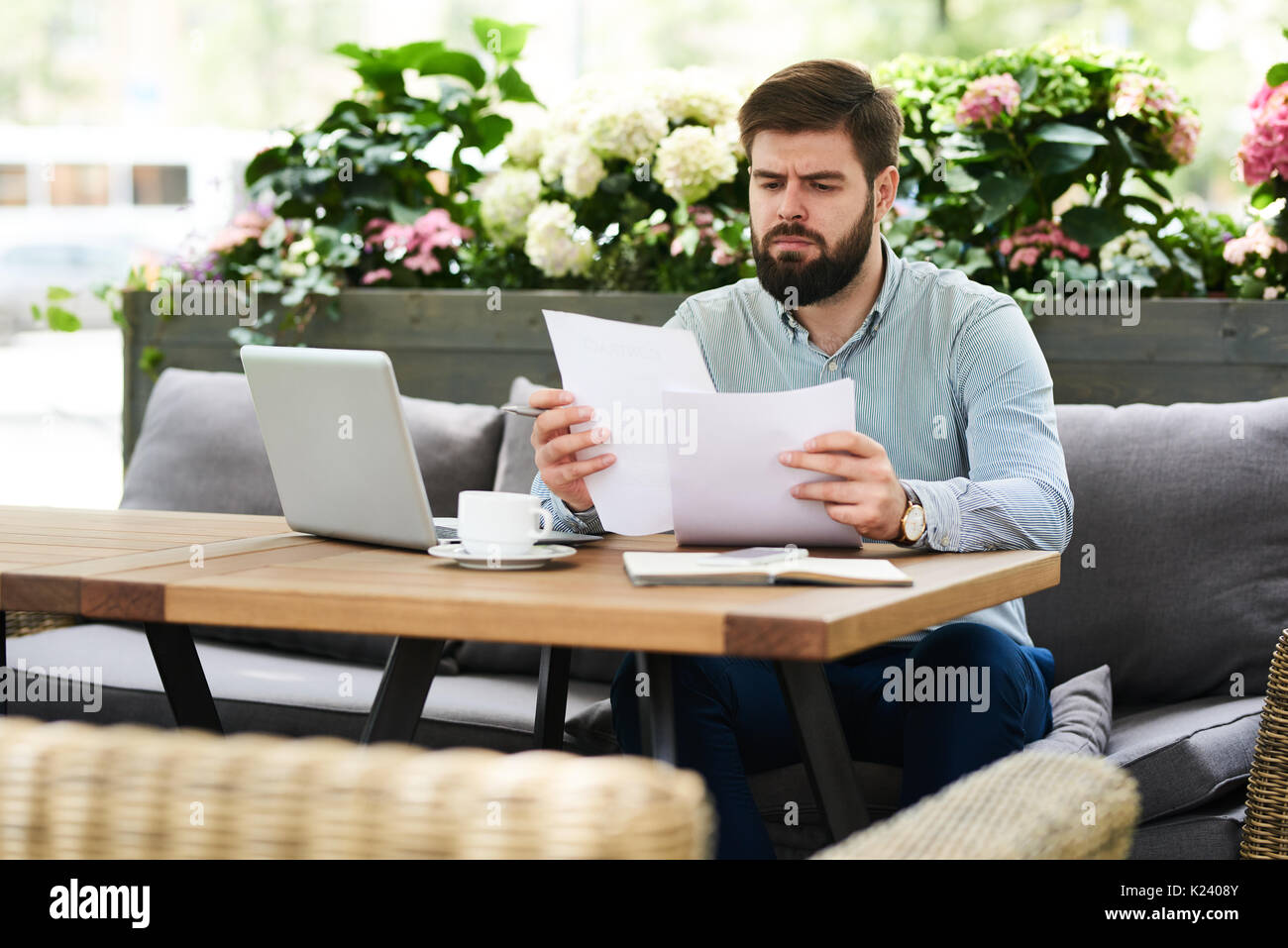 Frowning Businessman Reading Documents in Cafe Stock Photo