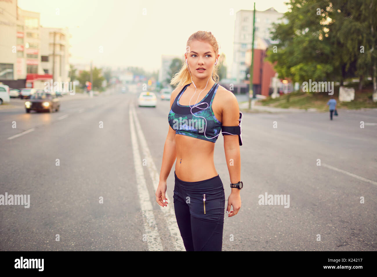Sporty girl runner on the road in the city streets. Stock Photo