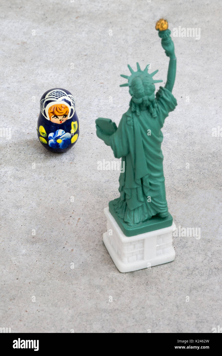 A model of the Statue of Liberty that is looking at a small Russian Matryoshka doll with the focus on the Matryoshka doll (concept) Stock Photo