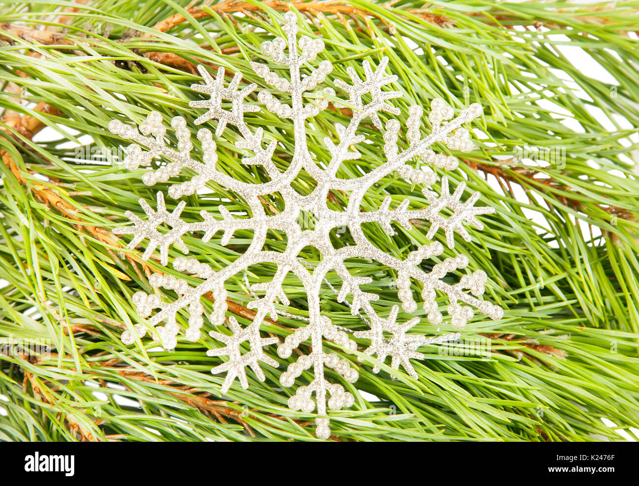 Artificial new year snowflake on fir tree branch background close up Stock Photo