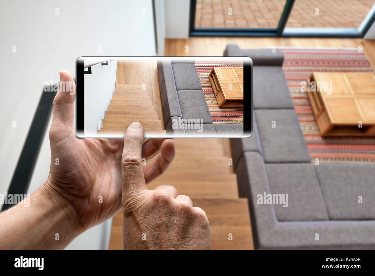 Two hands holding a mobile Smartphone taking picture on Hardwood stairs and ramp in modern renovated living room Stock Photo
