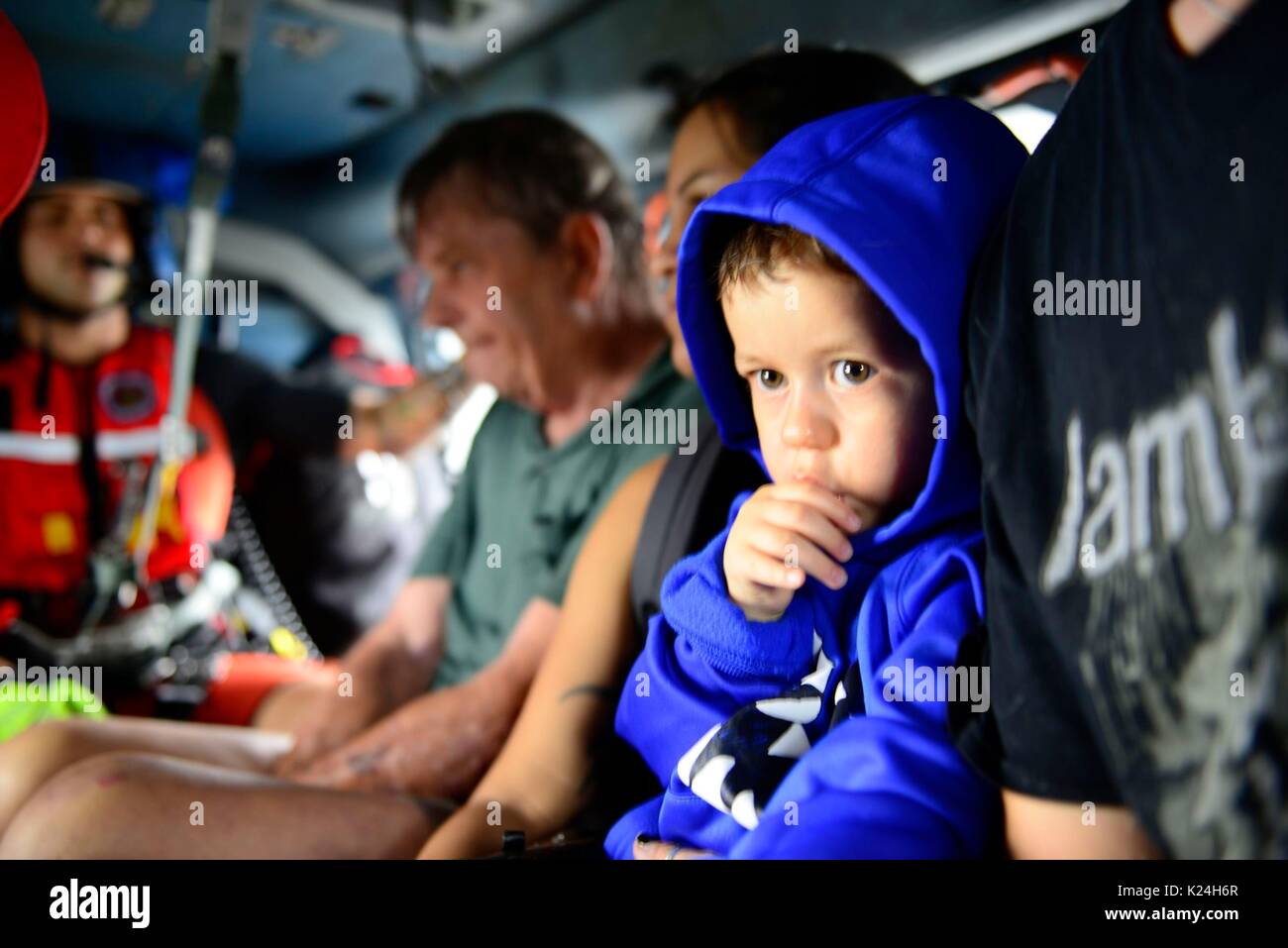 A young boy rests in a U.S. Coast Guard helicopter after being rescued from massive flooding in the aftermath of Hurricane Harvey August 27, 2016 in Houston, Texas. Stock Photo