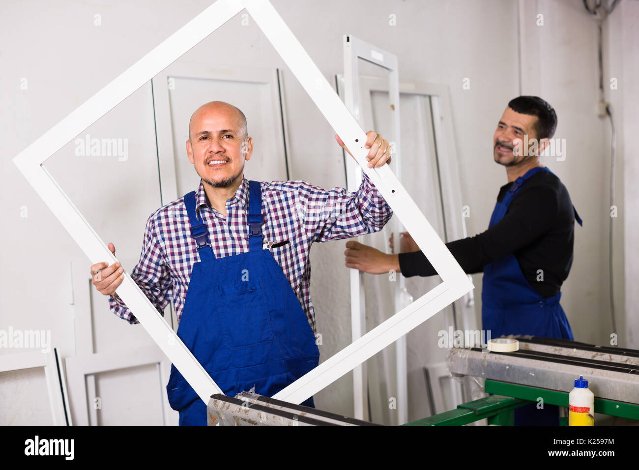 Two positive professional workmen in coverall with different PVC windows and doors Stock Photo
