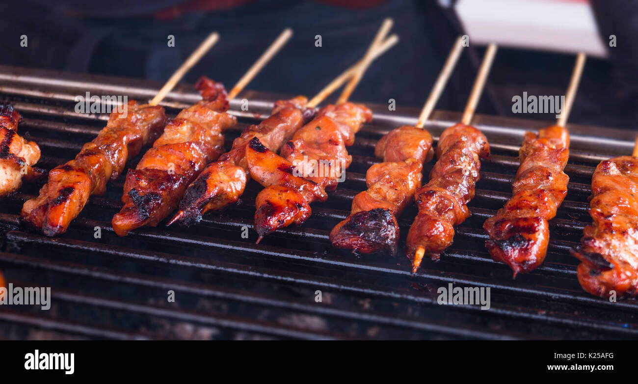 spicy roasted chicken sate/satay sticks lined up on a hot burning coal barbecue Stock Photo