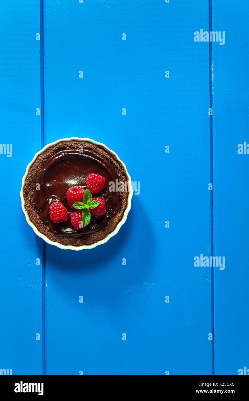 Chocolate raspberry tarts mint leaves on blue background Stock Photo