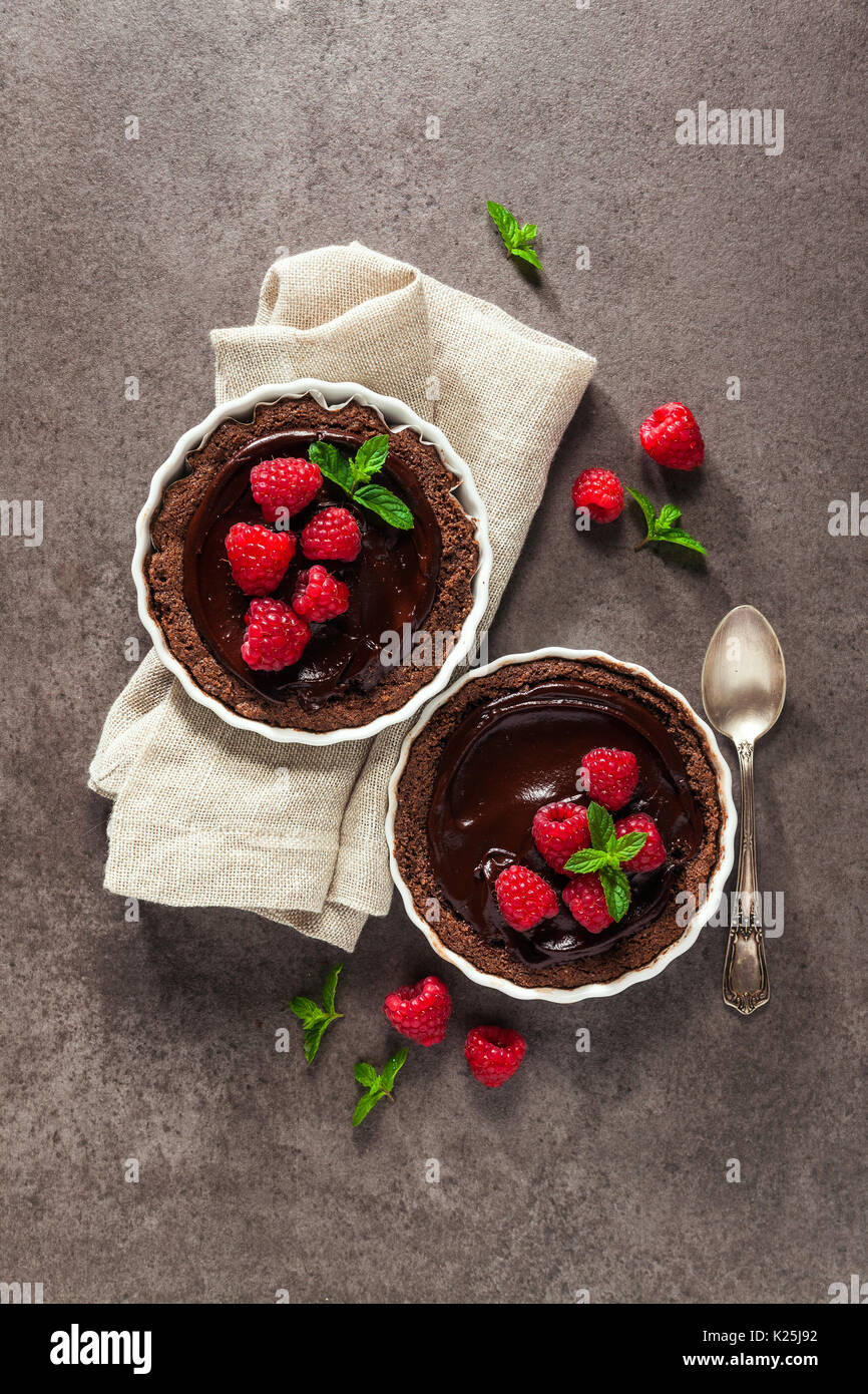 Chocolate raspberry tarts mint leaves on dark stone background Stock Photo