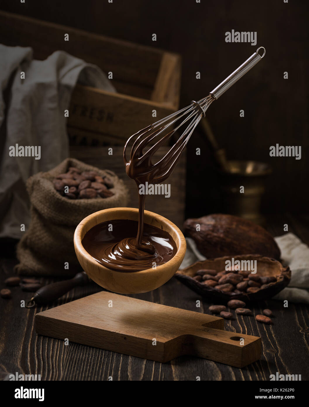 Dark still life with melted chocolate in wooden bowl Stock Photo