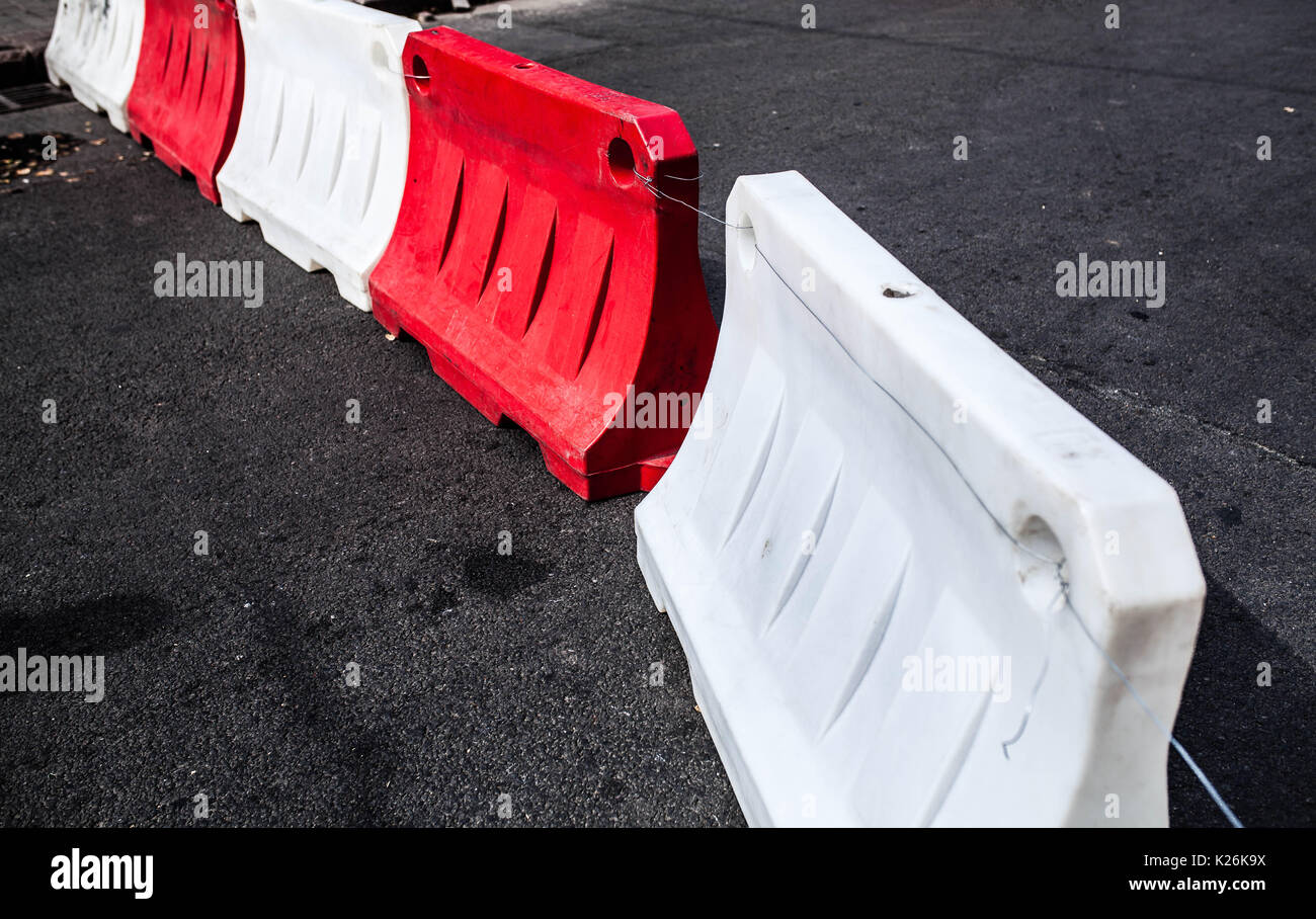 Red and white plastic barriers blocking the asphalt road Stock Photo