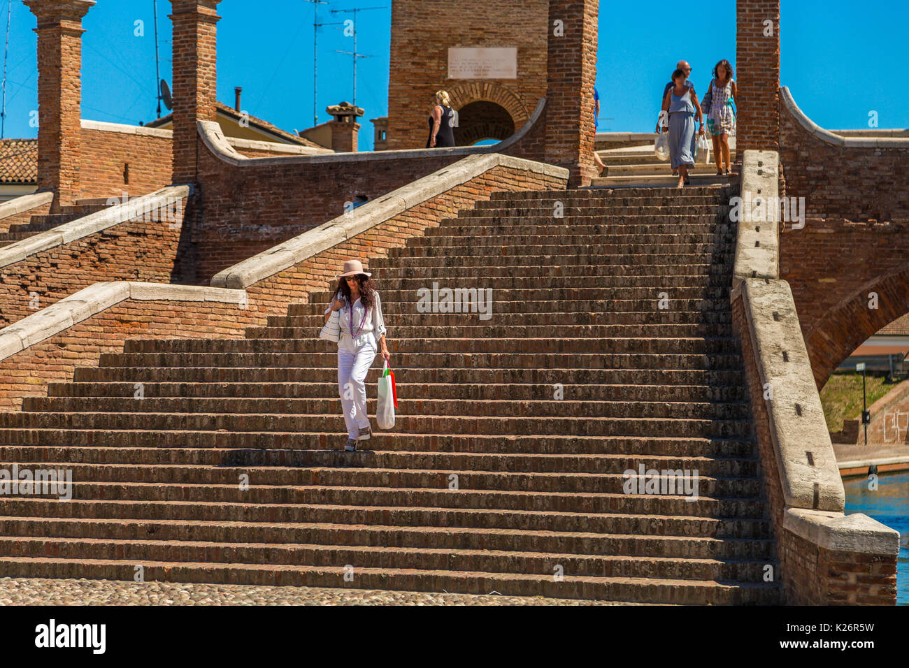 classy woman going downstairs from ancient bridge in Italy Stock Photo