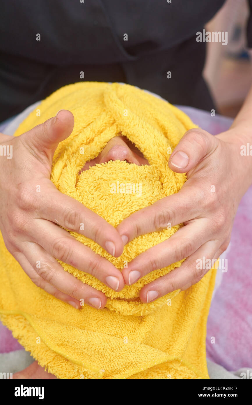 Hot towel face massage. Hands of masseuse. Stock Photo