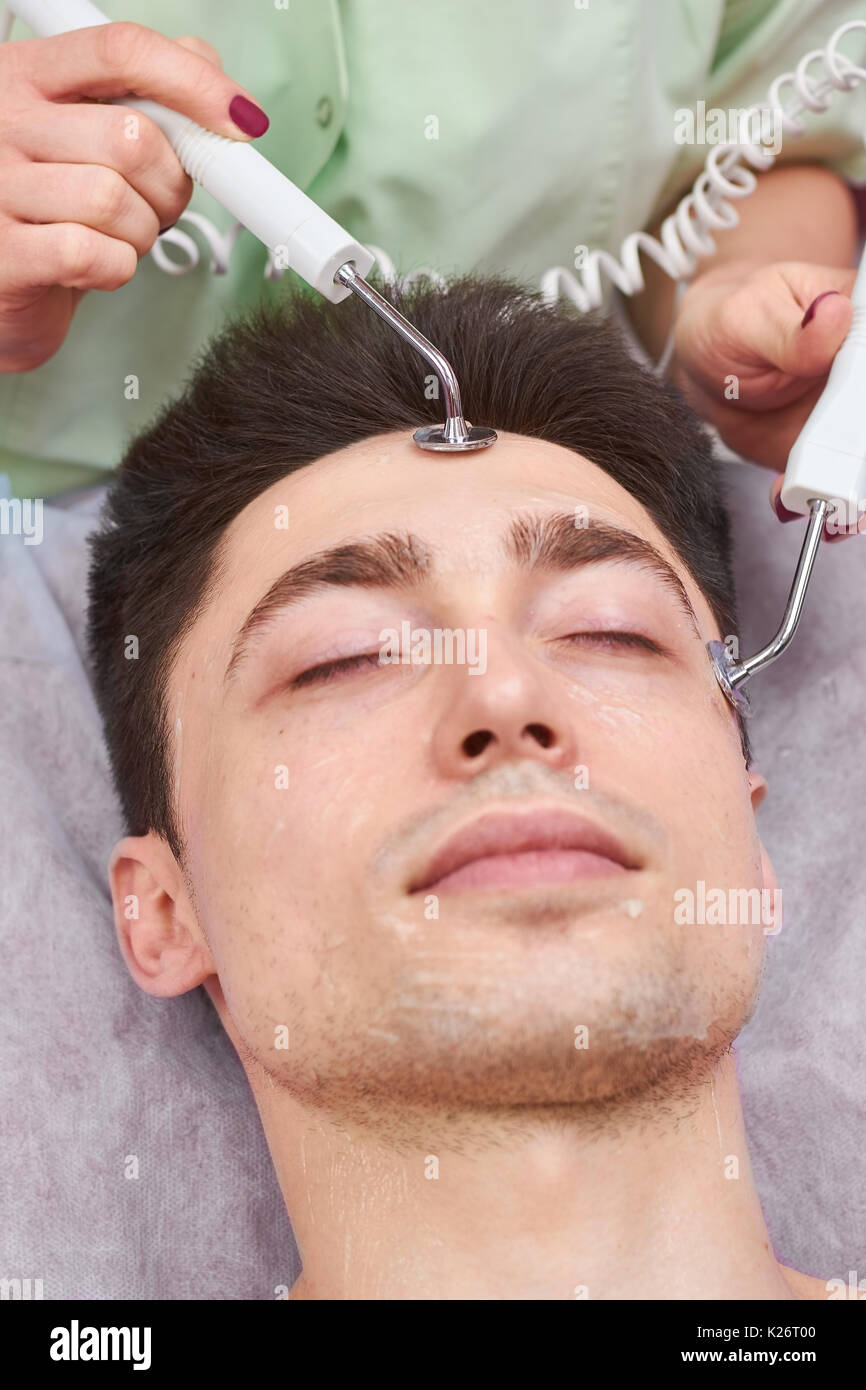 Male face, microcurrent therapy. Guy at the cosmetician. How effective is skin electrotherapy. Stock Photo