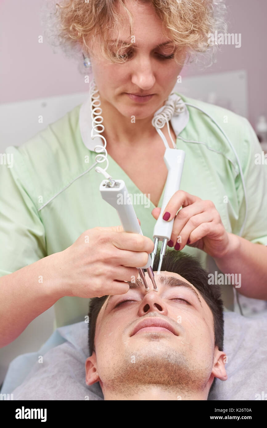 Woman using microcurrent therapy device. Cosmetician at work, skin ...