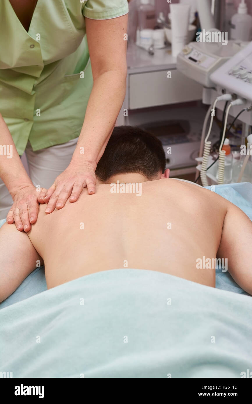 Guy having massage. Female hands massaging shoulder. Massage to relieve joint pain. Stock Photo