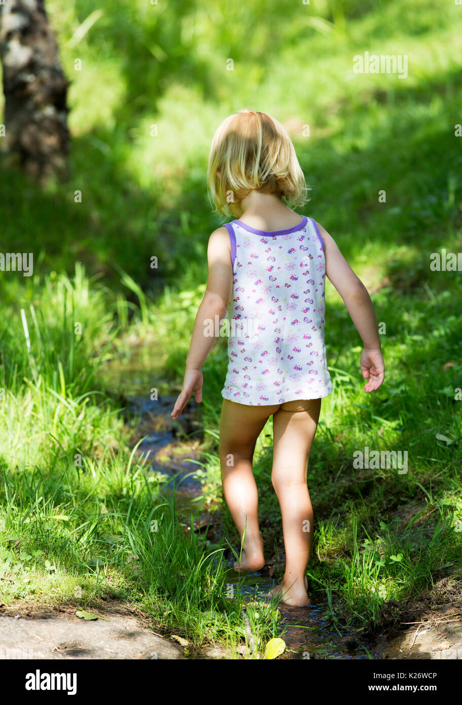 Toddler walking barefoot in the water, Germany Stock Photo