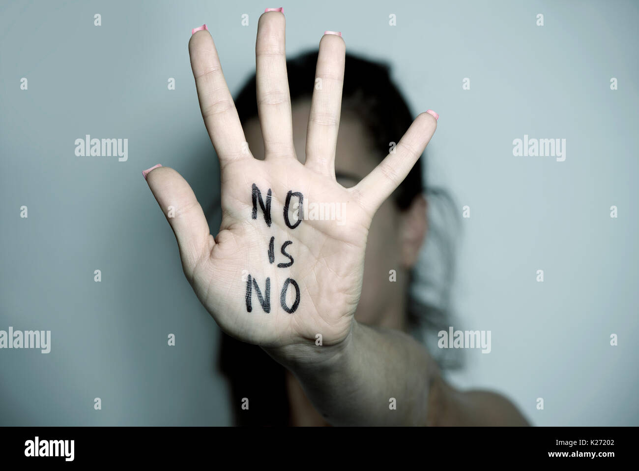 closeup of the hand of a young caucasian woman in front of her face with the text no is no written in her palm Stock Photo