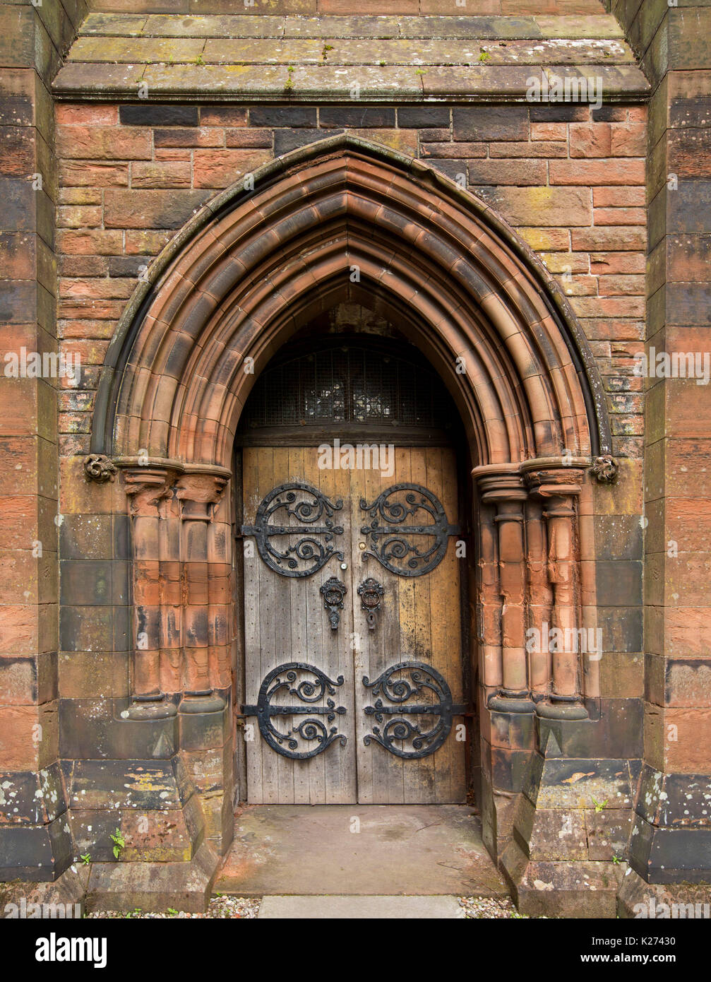 Arched door with huge & ornate hinges in imposing stone archway at entrance to historic Thomas Coats Memorial Baptist church in Paisley, Scotland Stock Photo