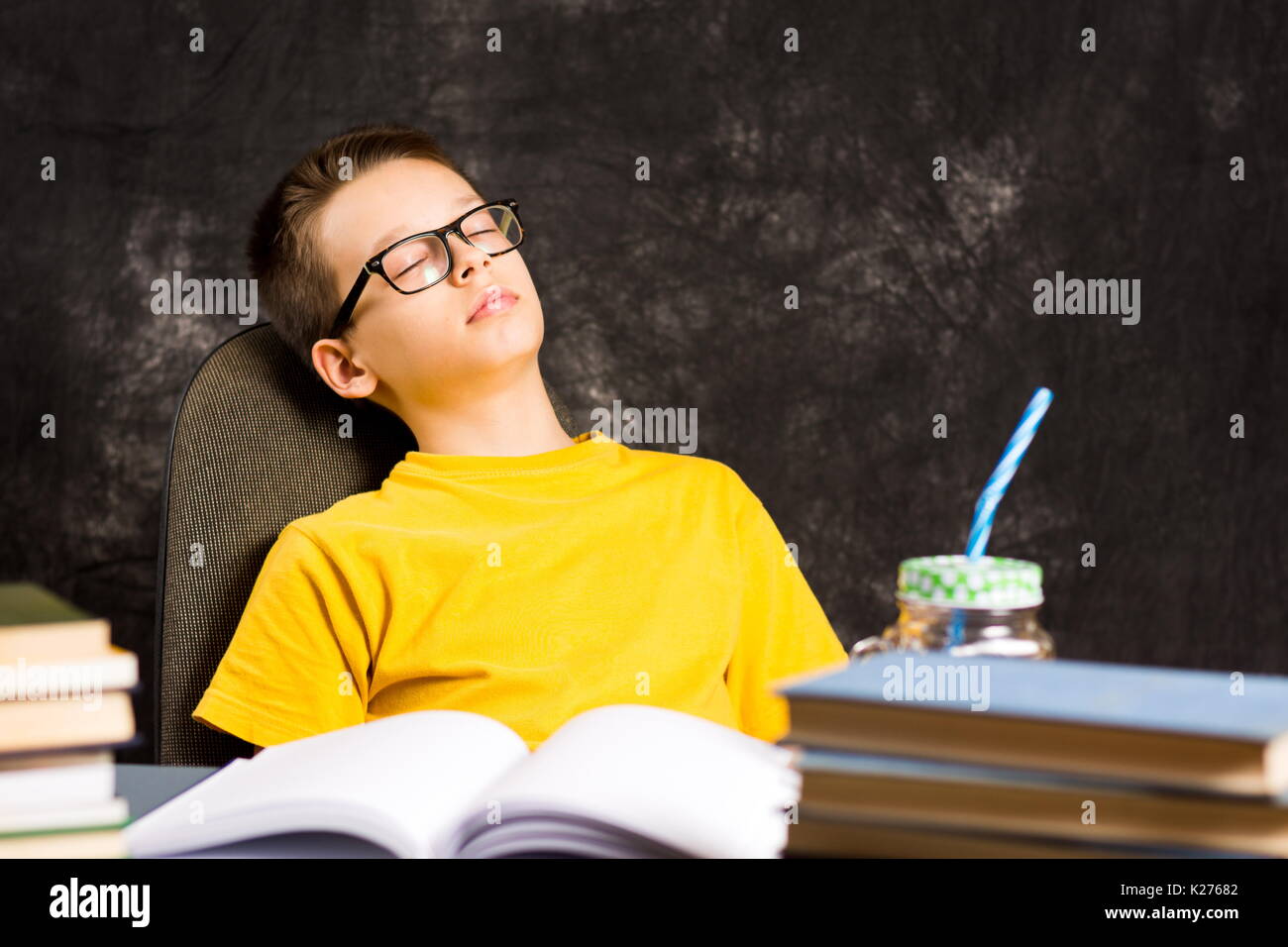 Boy taking a nap while finishing homework by the desk Stock Photo