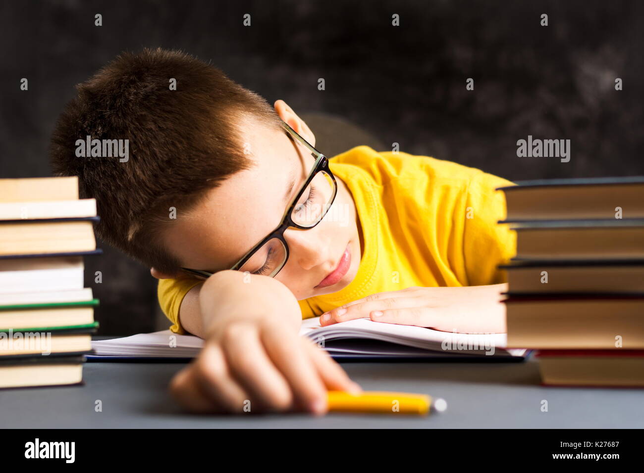 Boy taking a nap while finishing homework by the desk Stock Photo