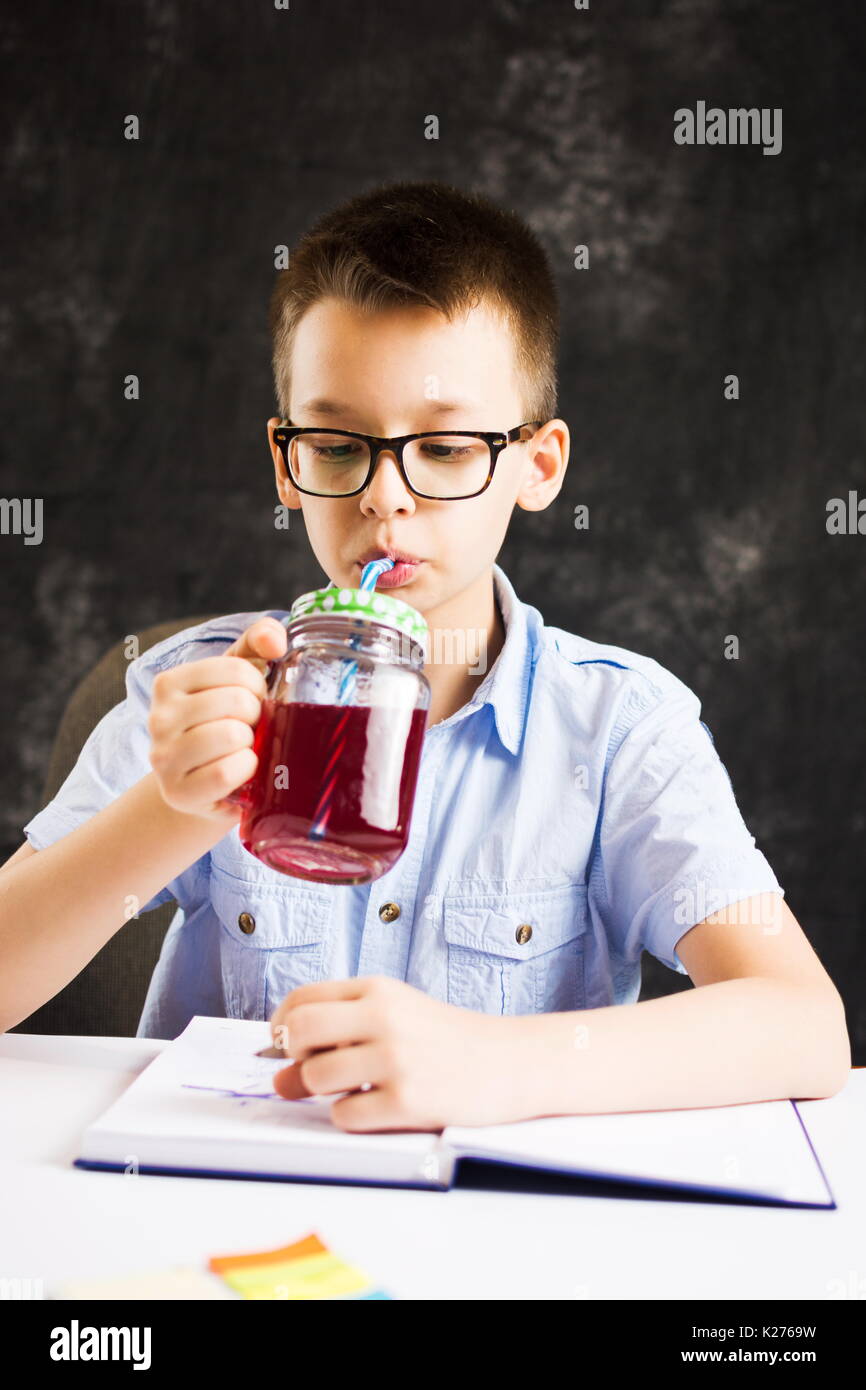 Boy drinking juice while finishing homework at home Stock Photo