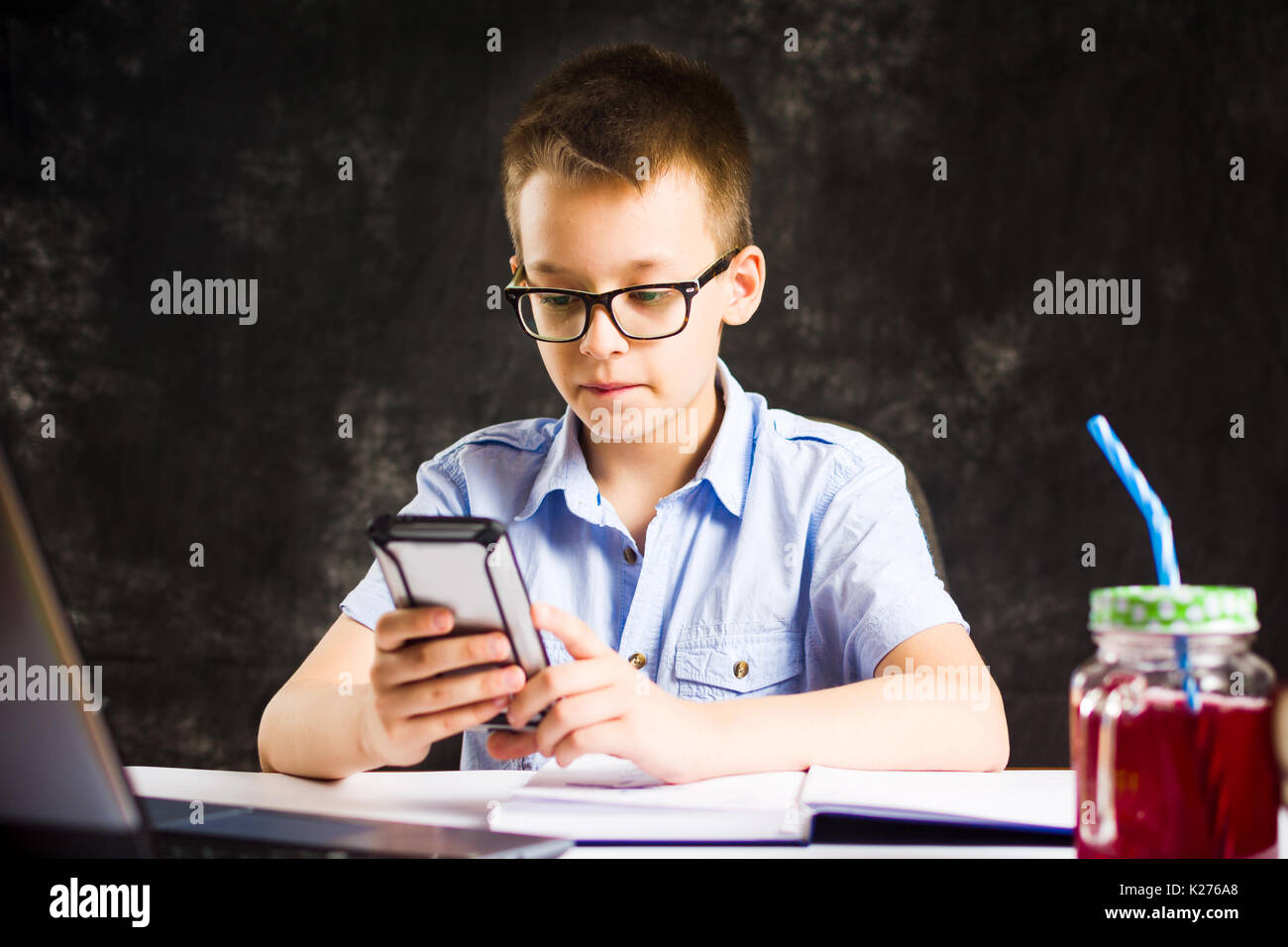 Boy playing the phone while doing homework at home Stock Photo - Alamy