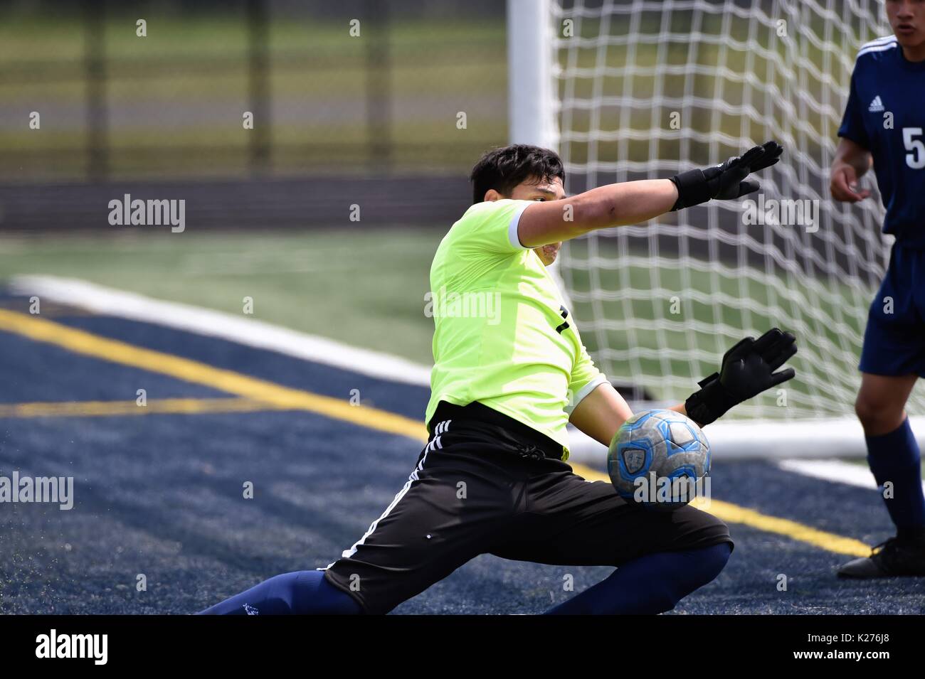 Keeper ranging out from his goal to make a stop on a centering pass destined for in front of his net. USA. Stock Photo