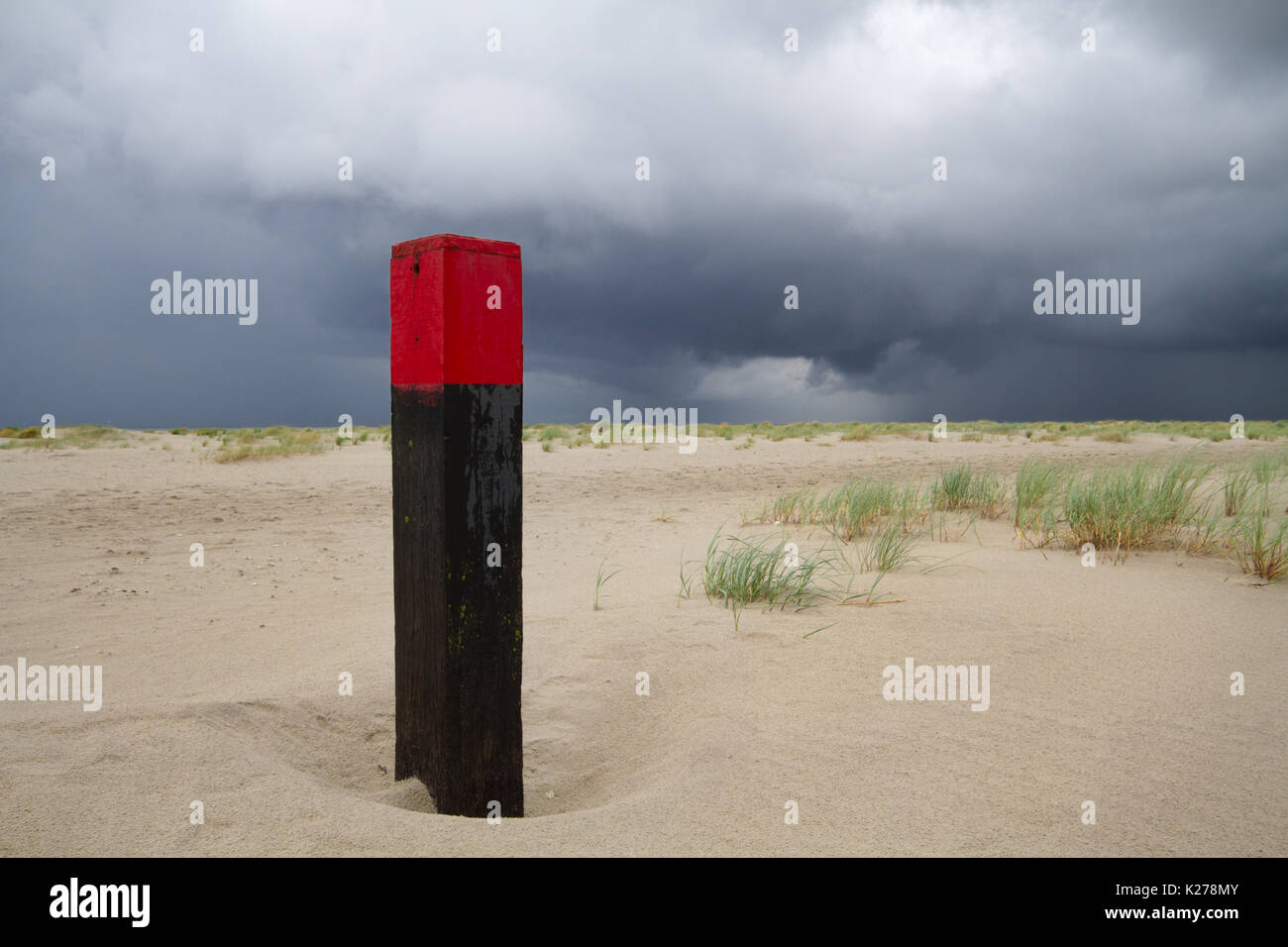 Beach pole on vast beach, threatening clouds above the sea Stock Photo