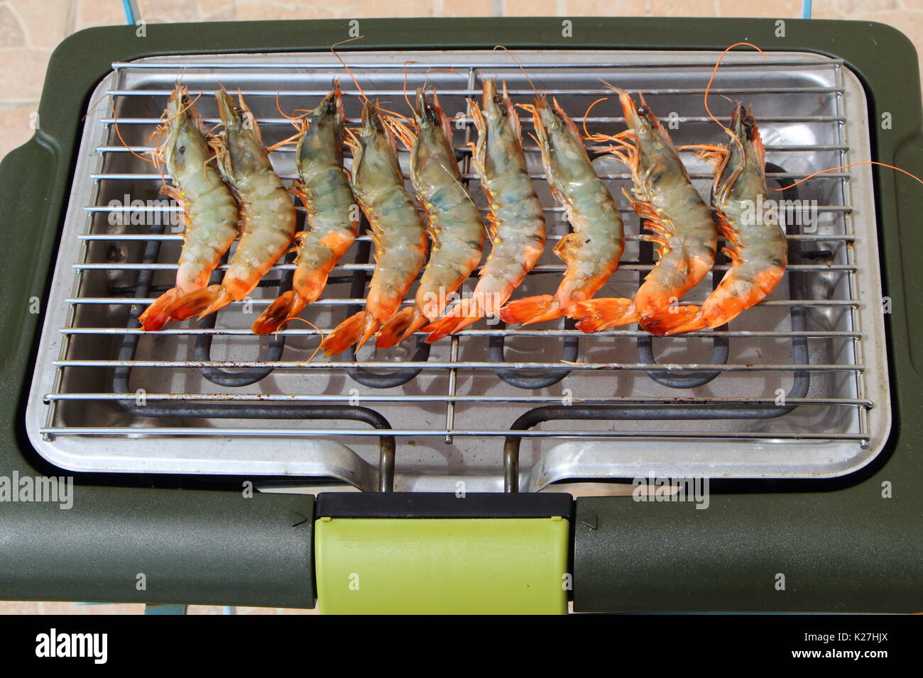 Raw fresh prawns on the rack of an electric barbecue Stock Photo