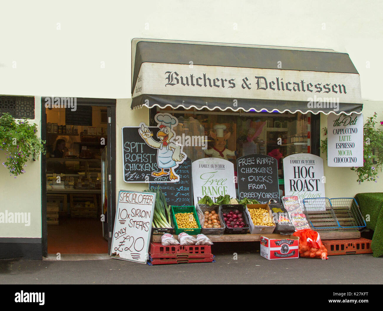 Butcher's shop and delicatessen with colourful display of fresh vegetables and sale signs on footpath at village of Mortonhampstead, Devon England Stock Photo