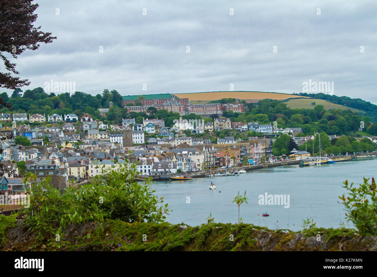 Coastal town of Dartmouth with houses crammed on tree-cloaked hillside rising above harbour dotted with boats in Devon, England Stock Photo
