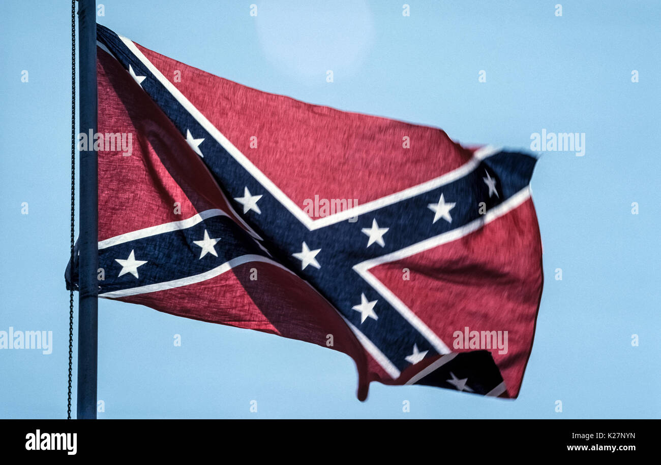 A flag currently flown to represent the now-defunct Confederate States of America is whipped by the wind on a flagpole in Tennessee, USA, one of the 13 states of the Confederacy represented by the 13 white five-pointed stars on two crossed blue bands trimmed with white against a red background. It is one of several flag designs used by Confederates fighting for the South during America's Civil War between 1861-1865. Stock Photo
